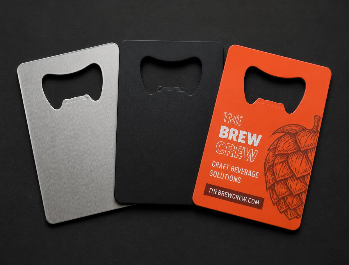 three metal business cards side by side in brushed steel, matte black, and orange accent finishes